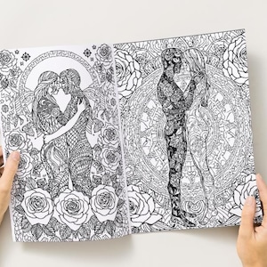 May include: Open coloring book pages featuring intricate black and white illustrations of embracing figures, surrounded by floral and geometric patterns. The pages are held open, showcasing the detailed artwork.