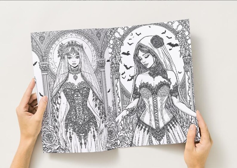 Puede incluir: Una p&aacute;gina doble de un libro para colorear en blanco y negro con dos ilustraciones g&oacute;ticas de mujeres con elaborados vestidos y velos. Los dibujos incluyen elementos florales y arquitect&oacute;nicos detallados, con murci&eacute;lagos en el fondo. El libro est&aacute; abierto por manos.