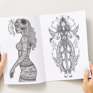 Peut inclure: Livre ouvert avec deux illustrations d&eacute;taill&eacute;es en noir et blanc. L'une repr&eacute;sente une femme tatou&eacute;e, un croissant de lune et une fleur dans les cheveux. L'autre montre une femme ail&eacute;e avec un design orn&eacute;.