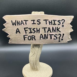 May include: A wooden sign with a rustic finish and a whimsical message: "What is this? A fish tank for ants?!"