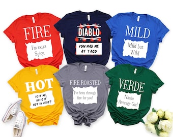 May include: Six colourful t-shirts with text. The red shirt says "FIRE" and "I'm extra Spicy." The navy shirt says "DIABLO" and "YOU HAD ME AT TACO." The blue shirt says "MILD" and "Mild but Wild."