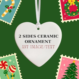 May include: A white heart-shaped ceramic ornament with the text "2 SIDES CERAMIC ORNAMENT ANY IMAGE/TEXT" in black and red. The ornament hangs from a white ribbon. The background features Christmas-themed postage stamp designs.
