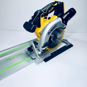 May include: A yellow and black DEWALT circular saw with a silver blade and housing, mounted on a silver guide rail with the word FESTOOL in green. The saw is designed for precision cutting.