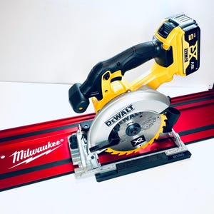 May include: A yellow and black DeWalt cordless circular saw with an XR battery pack attached, positioned on a long red Milwaukee track guide. The saw features a silver blade guard with the DeWalt logo and an XR emblem on the circular saw blade.