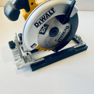 May include: A yellow and black DeWalt 18V circular saw. The saw blade is silver with the DeWalt logo and a black guard. The saw is designed for cutting wood and other materials. The saw is on a white surface.