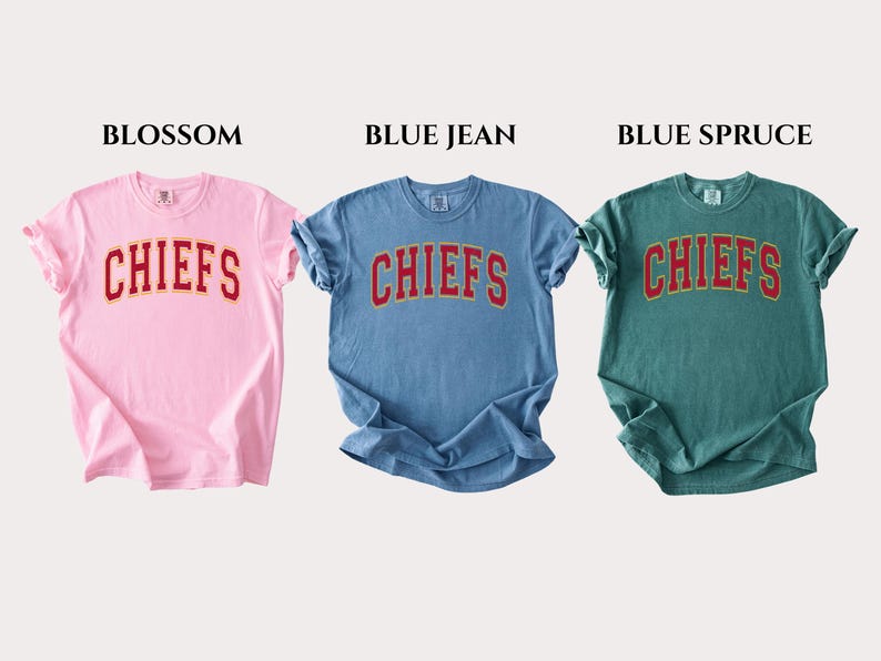 Op de afbeelding: Drie T-shirts met korte mouwen en ronde hals in lichtroze, middenblauw en donkergroenblauw. Elk shirt heeft het woord CHIEFS in een rood gebogen lettertype met een gele omlijning op de borst. De kleuren zijn Blossom, Blue Jean en Blue Spruce.