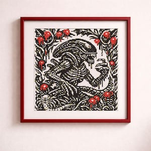 Peut inclure: Broderie au point de croix d'un Alien en noir et blanc, encadrée dans un cadre en bois rouge. Le motif comprend des touches de rouge et une bordure florale, créant une œuvre d'art détaillée.