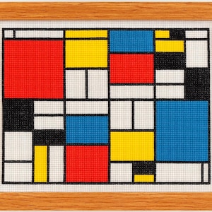 Puede incluir: Obra de arte abstracta enmarcada en madera. La obra presenta una cuadrícula de bloques de colores en rojo, amarillo, azul, negro y blanco. El diseño recuerda al movimiento artístico De Stijl. El marco es de madera marrón claro.