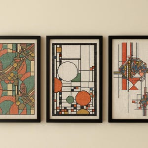 Könnte beinhalten: Drei gerahmte abstrakte Kunstwerke. Das Kunstwerk zeigt geometrische Designs mit Kreisen, Quadraten und Linien in Orange, Grün und Blau auf weißem Hintergrund. Die Rahmen sind schwarz.