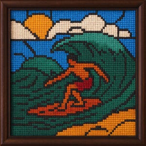 May include: Framed cross-stitch art depicting a surfer riding a large wave. The artwork features a blue sky with a yellow sun and white clouds. The surfer is orange and red, the wave is green, and the sand is orange.