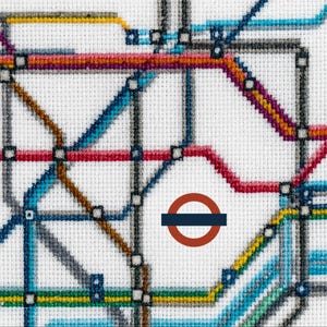 Op de afbeelding: Een kruissteekafbeelding van de Londense metrokaart. Het ontwerp toont kleurrijke lijnen, waaronder rood, blauw, geel en grijs, die metrolijnen vertegenwoordigen, tegen een witte achtergrond. Het iconische ronde logo is zichtbaar.