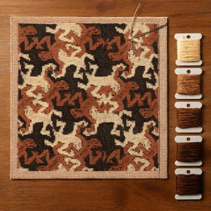 May include: A square, patterned needlepoint project in progress, featuring a repeating design in black, beige, and rust-brown. A needle and thread are in the upper right corner. Spools of thread in various shades of brown and beige are arranged vertically.