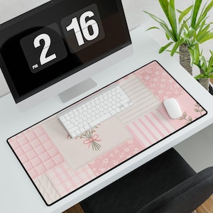 Peut inclure: Un tapis de bureau rectangulaire présentant un motif patchwork dans des tons rose clair et blanc. Le design comprend des sections avec des imprimés floraux, des rayures verticales, une texture matelassée et un bouquet noué d'un ruban rose.