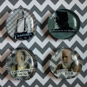 May include: Four round glass magnets with images of older men. One says "GANSTA", another "Forever in our hearts", a third "I ain't showing you my leg!", and the last "TOUGH SOB". The background is a gray and white chevron pattern.