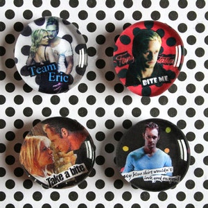 May include: Four round, glass-covered buttons with images and text. One says "Team Eric", another "BITE ME", a third "Take a bite", and the last "My blue shirt wouldn't look good on you!". The buttons are on a black and white polka dot background.