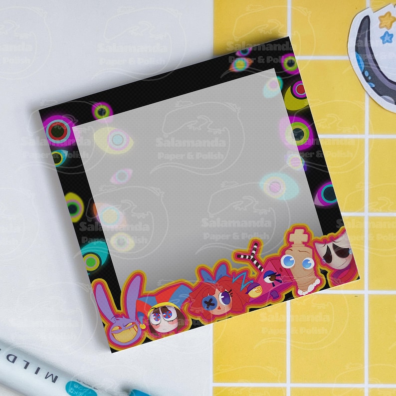 May include: A square notepad with a black border featuring colorful cartoon faces and eye designs. The notepad has a transparent overlay with the text "Salamanda Paper & Polish". A sticker with a star and octopus is visible.