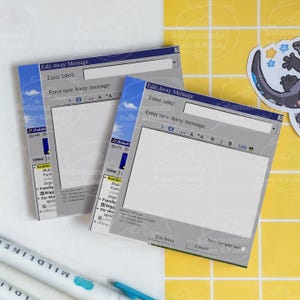 May include: Two square notepads with a retro computer interface design, featuring text fields and buttons. The pads are blue and grey, with the words "Edit Away Message" visible. A salamander sticker is in the background.