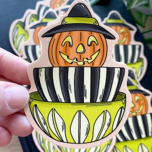 May include: A set of three Halloween-themed stickers featuring a jack-o'-lantern wearing a witch's hat and sitting in a striped pot with a green base.