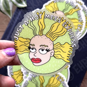 May include: A clear sticker featuring a cartoon character with yellow hair and red lips. The character is surrounded by a green circle with the text "JUST A HOT MESS EXPRESS" in white. Several stickers are visible.