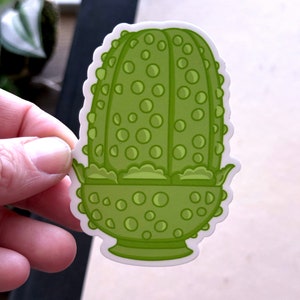 May include: Green cartoon sticker of a plant with a bulbous, round, textured body and a green, scalloped, bowl-shaped base.