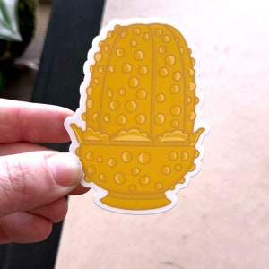 May include: A gold-colored glass bowl with a textured, bubble-like design. The bowl is shaped like a flower with a rounded base.