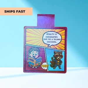 May include: A comic book-themed card with a boy reading a comic and a raccoon superhero. The text reads "Reality is overrated, give me a talking raccoon..." and "POOF!" in a speech bubble. The card is red and purple.