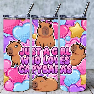 May include: Pink, blue, and purple tumbler with a capybara theme. The tumbler features cartoon capybaras, hearts, stars, and the text "Just a Girl Who Loves Capybaras". Includes a silver straw.