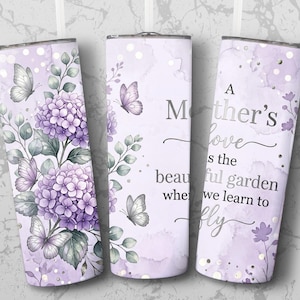 Puede incluir: Tres vasos de acero inoxidable con un diseño floral. Los vasos presentan hortensias moradas, mariposas y el texto "A Mother's love is the beautiful garden where we learn to fly" sobre un fondo lavanda.