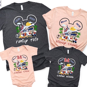 May include: Four matching t-shirts and a onesie with a Disney cruise theme. The shirts are gray and pink, and the onesie is pink. Each item features a Mickey Mouse head design with the name "Olivia" and the year "2026", along with the phrases "Family Trip", "Disney Cruise", "Cruise Crew", and "Cruise Squad".