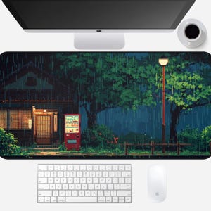 May include: A pixel art mousepad featuring a rainy night scene with a Japanese-style building, a red vending machine, and a street lamp. The design includes lush green trees and a dark, moody sky. A white keyboard, mouse, and computer monitor are also visible.