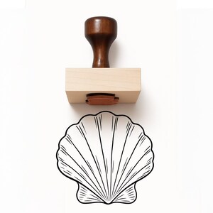 May include: A wooden stamp with a dark brown handle and a light-colored rectangular base. The stamp features a seashell design in black ink. The stamp is designed for crafting and creating unique designs.