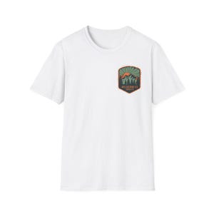 Camiseta com estampa "A Natureza Selvagem Aguarda" ao pôr do sol na montanha | distintivo para camping e trilhas ao ar livre