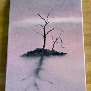 May include: An original painting on canvas depicts a silhouetted tree against a pink and purple sky. The tree's dark branches reach upwards, with a dark shadow extending downwards. The artwork is mounted on a wooden easel.