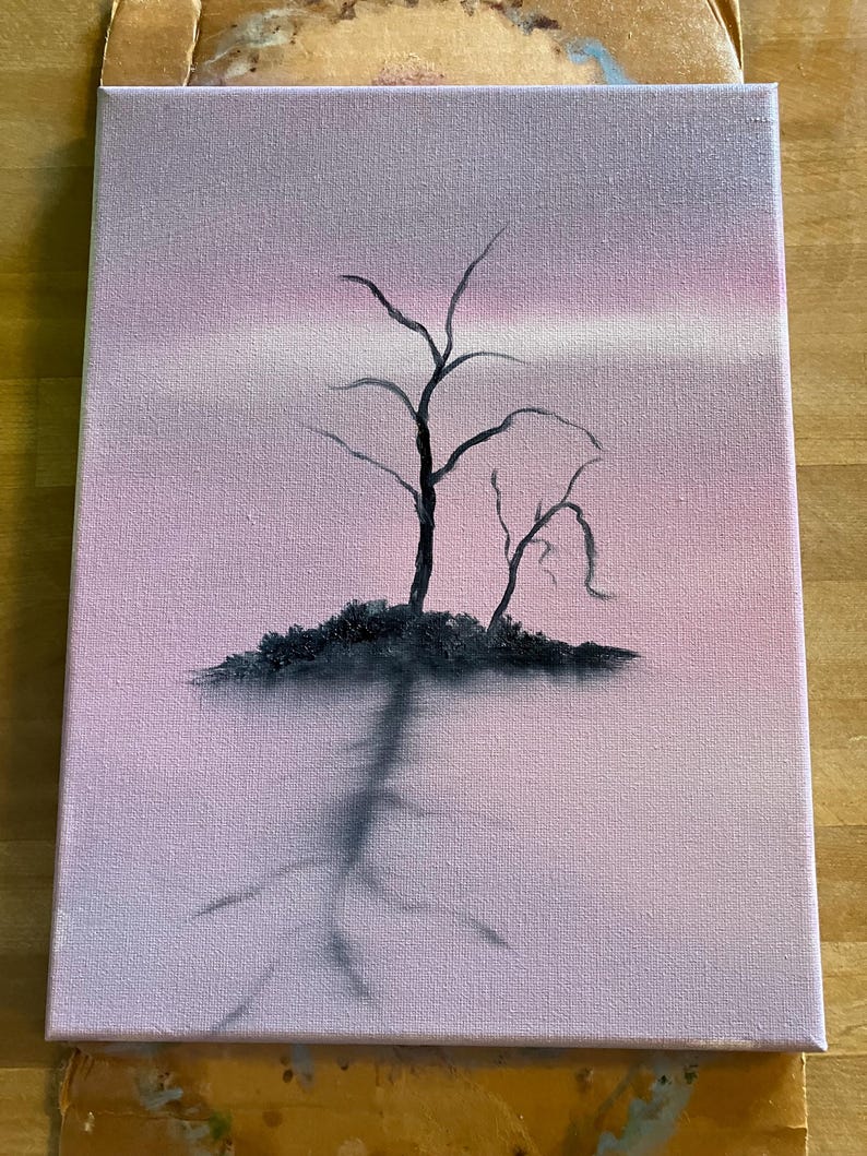 May include: An original painting on canvas depicts a silhouetted tree against a pink and purple sky. The tree's dark branches reach upwards, with a dark shadow extending downwards. The artwork is mounted on a wooden easel.