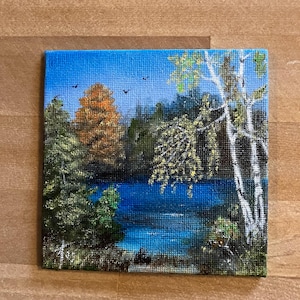 May include: A painting of a lake scene with trees and a blue sky. The trees are green and brown, and the lake is a bright blue. There are birds flying in the sky.