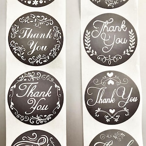May include: Eight round black and white thank you stickers with decorative flourishes. The stickers have a chalkboard background and white text.