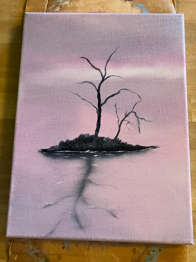 May include: A canvas painting depicts a serene landscape. Silhouetted black trees stand on a small island, reflected in the water below. The sky transitions from a soft pink to a lighter hue, creating a tranquil atmosphere. The artwork is mounted on a wooden easel.
