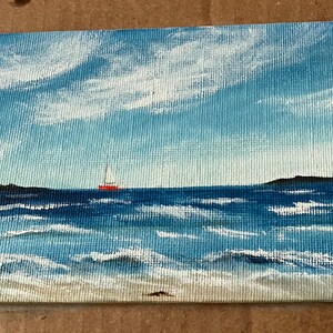 May include: A painting of a seascape with a red sailboat on the water. The sky is blue with white clouds and the water is a deep blue with whitecaps.