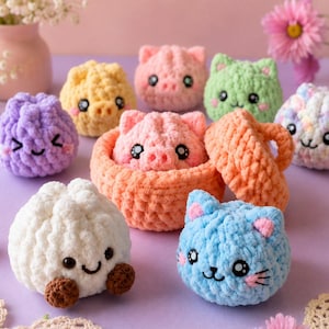 May include: A collection of small, round, crocheted plush figures featuring various animal and food-inspired designs in pastel colors. The set includes a white dumpling-like figure, a blue cat, a purple face, a yellow pig, and a peach-colored basket.