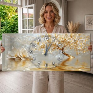 May include: A rectangular wall clock featuring a printed image of a golden tree with white blossoms reflected in water. The clock face has white numbers from 1 to 12 arranged in a circle, with two blue hands positioned near the center of the display.