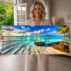 May include: A rectangular wall clock featuring a panoramic beach scene with turquoise water, a sandy shore, dark rocks, and a palm tree. The clock face is overlaid with a circular black frame and Roman numerals, with gold-colored hour and minute hands.