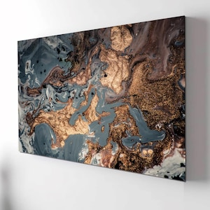 Puede incluir: Impresión artística abstracta con un diseño arremolinado en tonos grises, marrones y dorados. La obra de arte tiene un efecto marmolado con acentos dorados metálicos, creando una estética lujosa y moderna. El lienzo rectangular está montado en una pared blanca.