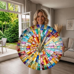 Puede incluir: Un reloj de pared redondo con un vibrante patrón de vidrieras multicolor y diseño radial. La esfera del reloj muestra manecillas de color dorado y números romanos negros dispuestos en un borde circular sobre los segmentos de vidrio.