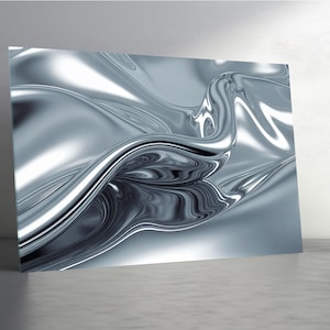 Op de afbeelding: Abstracte kunstprint met een vloeiend, metallic zilver design. Het kunstwerk heeft een glanzend, reflecterend oppervlak met dynamische rondingen en highlights, waardoor een gevoel van beweging en diepte ontstaat. De print is gemonteerd op een rechthoekig paneel.