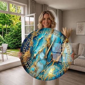 May include: A round wall clock featuring a blue and gold marbled pattern on the face. The clock has gold-colored Roman numerals and matching gold hands. The design displays a swirling mix of deep blue, light blue, and metallic gold veins.