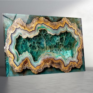 May include: A rectangular wall art print featuring a detailed depiction of a geode. The artwork showcases a vibrant color palette of teal, gold, and green, with intricate layers and textures. The geode's center is a deep green, surrounded by gold and teal.