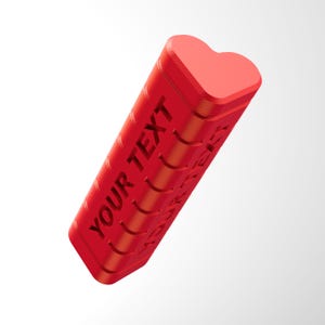 Puede incluir: Un objeto rectangular rojo con una parte superior en forma de corazón. El lateral del objeto tiene grabadas las palabras "YOUR TEXT" y "WORDS". El objeto es de color rojo vibrante y está sobre un fondo blanco.