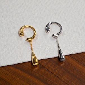 May include: Two ear cuff earrings. One is gold-toned, the other is silver-toned. Each earring has a curved upper portion and a dangling teardrop-shaped charm. The gold earring has a smooth, polished finish, while the silver earring has a textured chain.