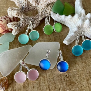 May include: Assortment of sea glass earrings in various colours, including pink, blue, and green. The earrings are made with silver-toned leverback fastenings.