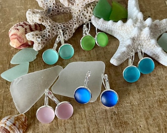 May include: Assortment of sea glass earrings in various colors, including pink, blue, and green. The earrings are made with silver-toned leverback closures.